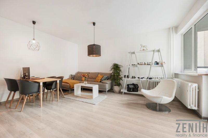 Living room in a two-room apartment with a light wood-patterned floor, modern furniture, and decorations.