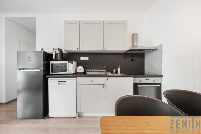 A kitchen in a 2-room apartment with equipment on a floor with a wooden decor.
