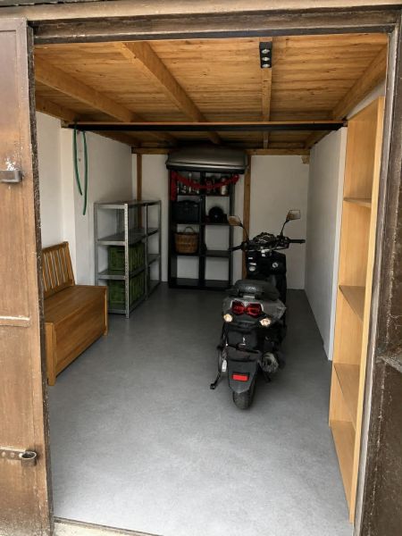 Garage with a motorcycle, wooden ceiling, and storage shelves.