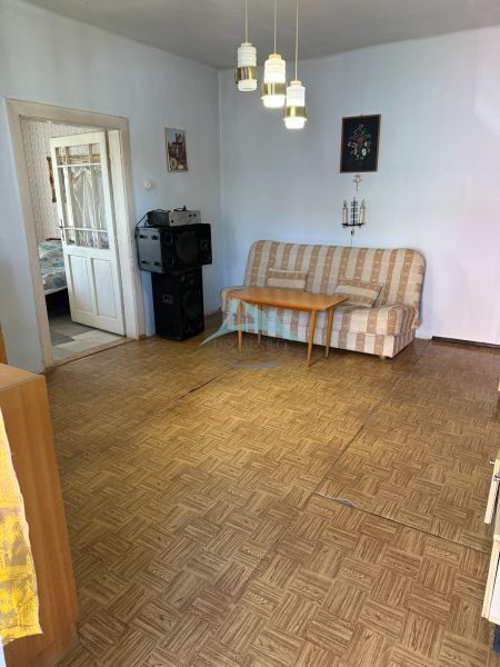 A living room in a family house with a sofa and a wood-patterned floor.