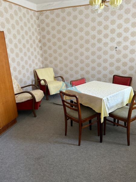 A room in a family house with retro furniture, wallpaper, and carpeted floor.