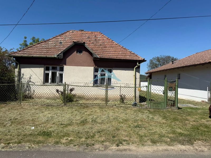 A family house in Hont has a sloped roof and is enclosed by a metal fence.