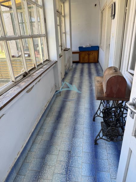 A hallway in a family house with blue tiles and large windows.