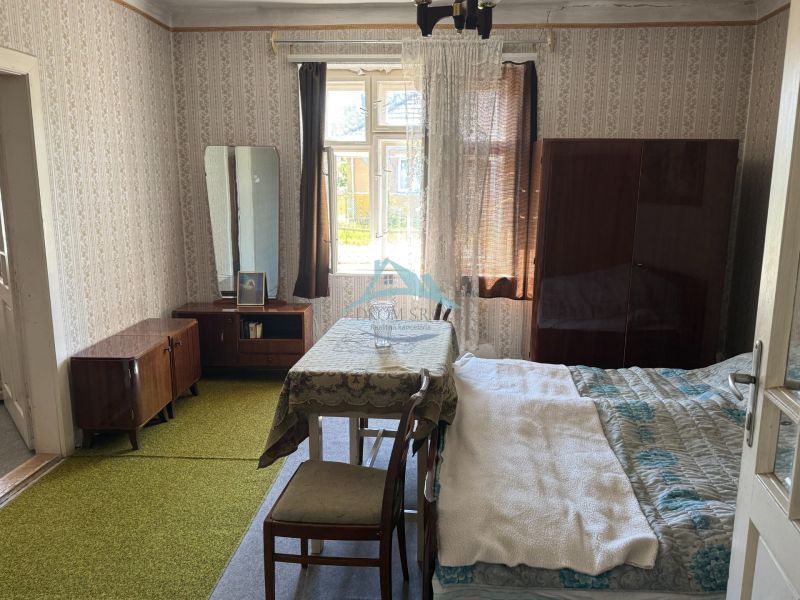 A room in a family house with 1960s furniture, wallpaper, and a green carpet.