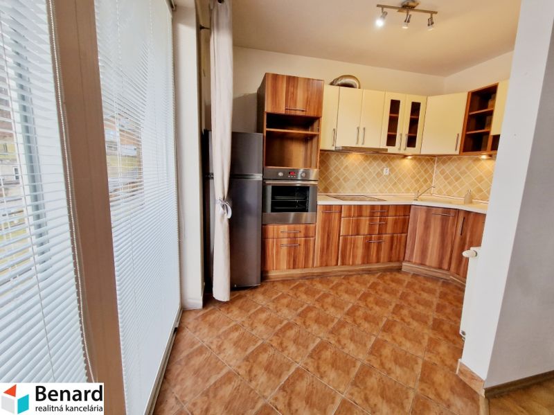 A kitchen with a kitchen unit and a wooden decor floor in a 3-room apartment.
