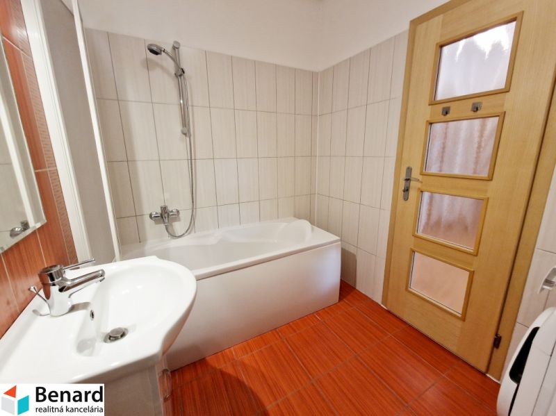 A bathroom with light tiles and red flooring in a 3-room apartment.