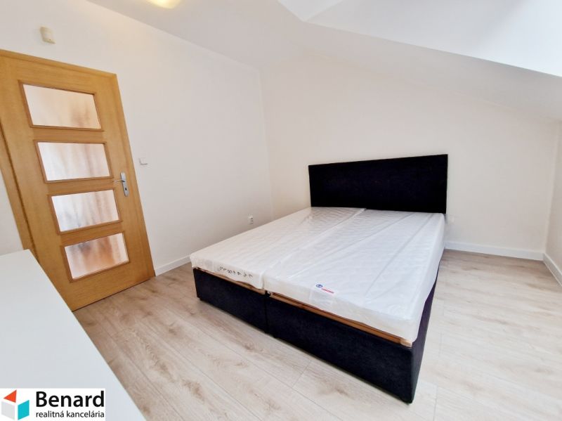 Bedroom with wood-patterned flooring in a 3-room apartment, simple bed.