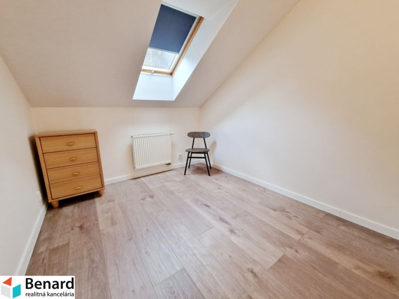 A room in a 3-room apartment with a wooden decor floor, a chest of drawers, and a chair.