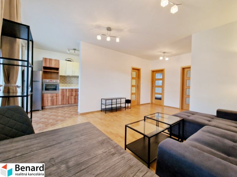 Living room in a three-room apartment with a gray sofa and a wooden-patterned floor.