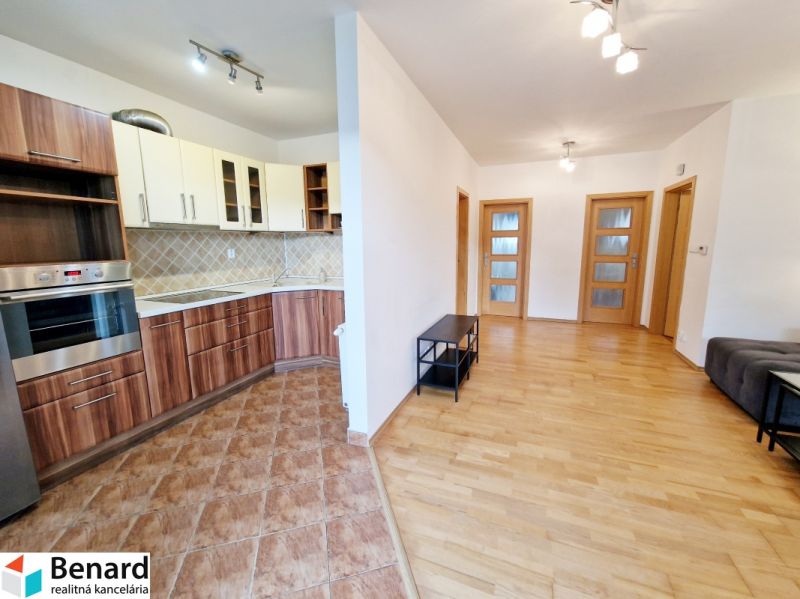 A kitchen in a 3-room apartment with built-in appliances and a wooden decor floor.