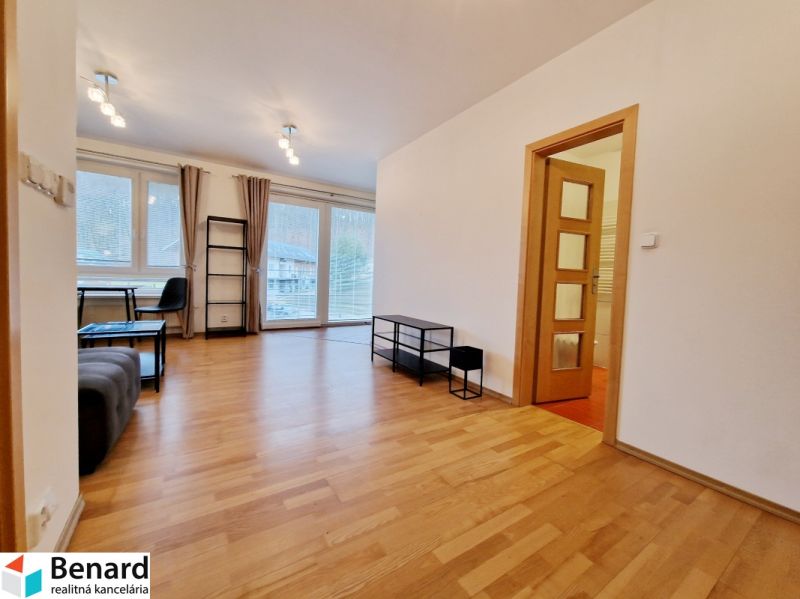 Living room with wood-patterned flooring in a three-room apartment.