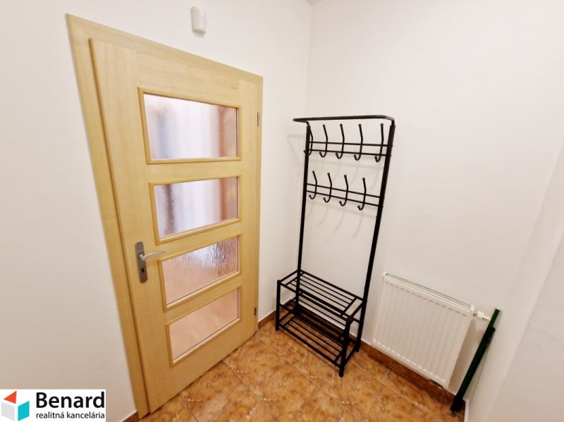 A hallway in a 3-room apartment with a coat rack, wooden doors, and a radiator.