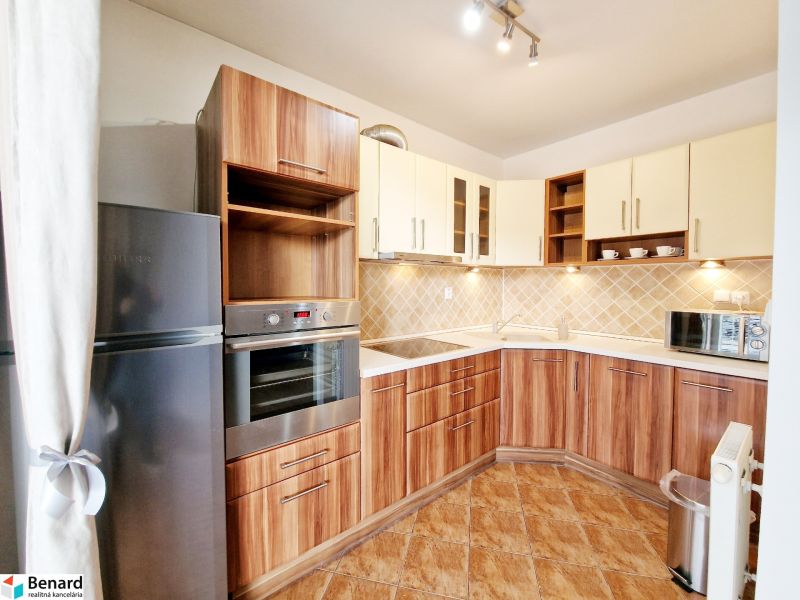 A kitchen in a 3-room apartment with a wooden decor floor and a corner kitchen unit.