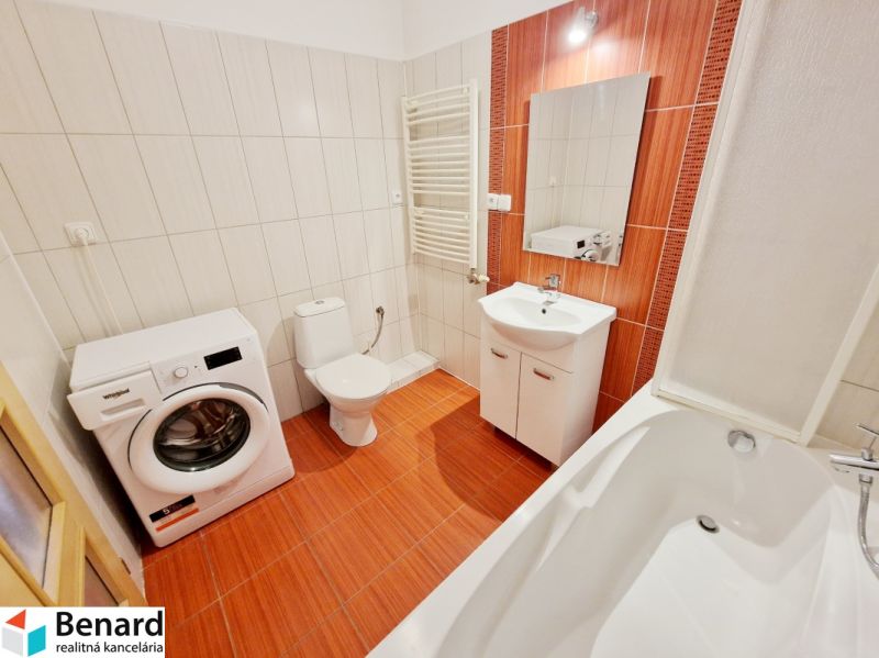 A bathroom in a 3-room apartment with a shower, a washing machine, and orange tiles.