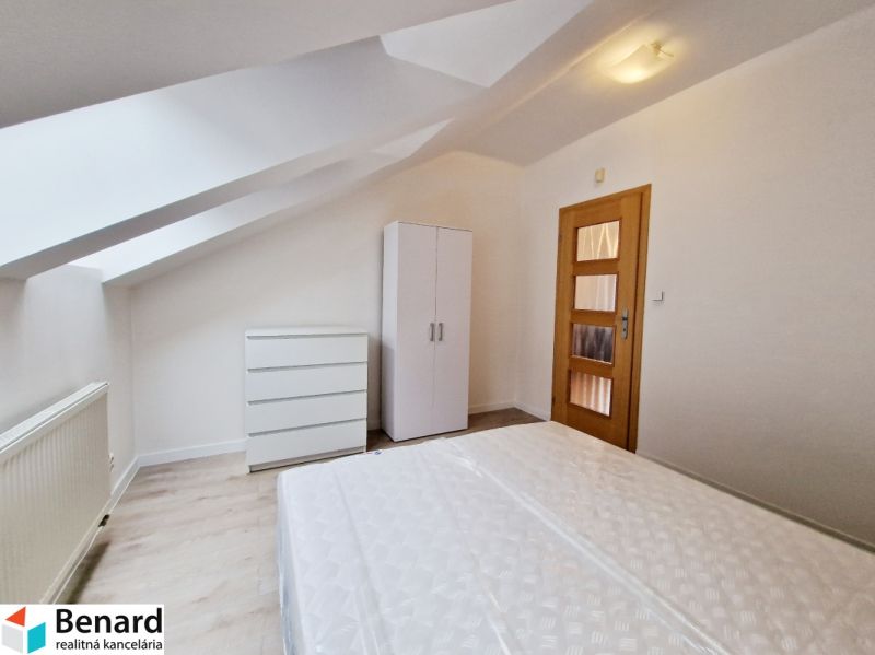 Attic bedroom in a 3-room apartment with white furniture and a wooden decor floor.