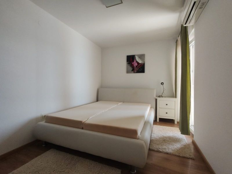Bright bedroom in a family house with a bed and wooden decor flooring.