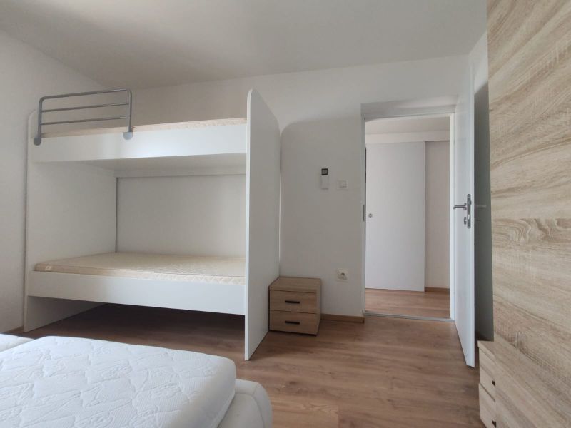 Bedroom with a bunk bed, wooden decor flooring, and storage space in a family house.