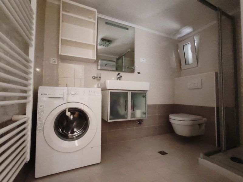 Bathroom in a family house with a washing machine, sink, shower, and toilet.