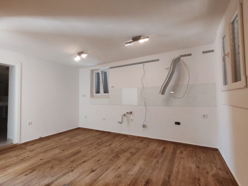 An empty kitchen in a family house with a wood-patterned floor.