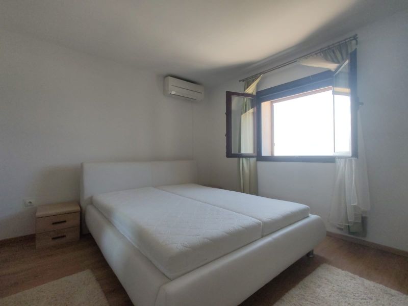 Bedroom in a family house with a large window and a bed, floor with wooden decor.