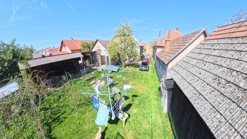 The garden of a family house in the village of Svinná with a car, a shelter, and a clothesline.