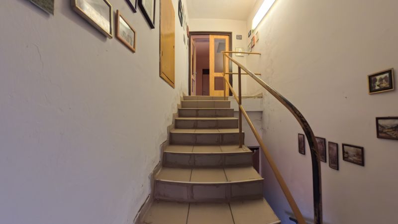 A staircase with a wooden railing in a family house, decorated with pictures.