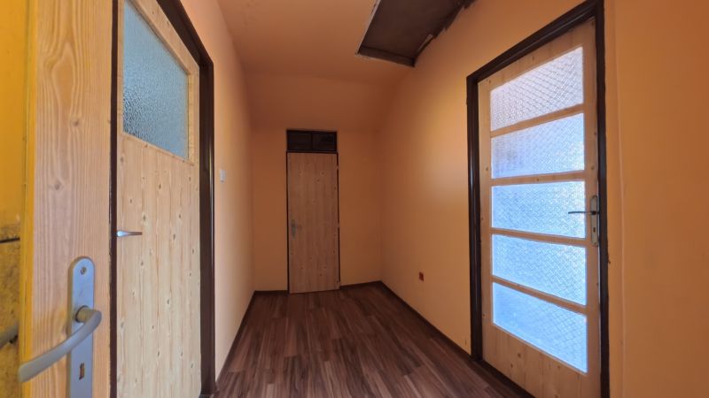 A hallway in a family house with a wooden decor floor and glass doors.