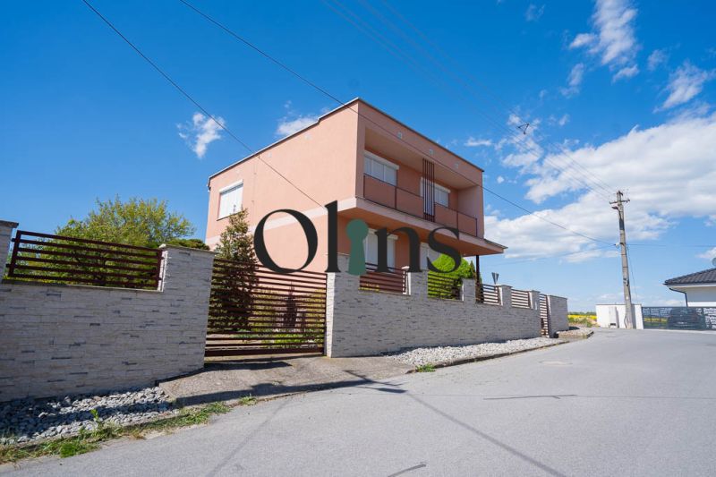 A family house on B. Tablica Street in Dudince with a stone fence and blue sky.
