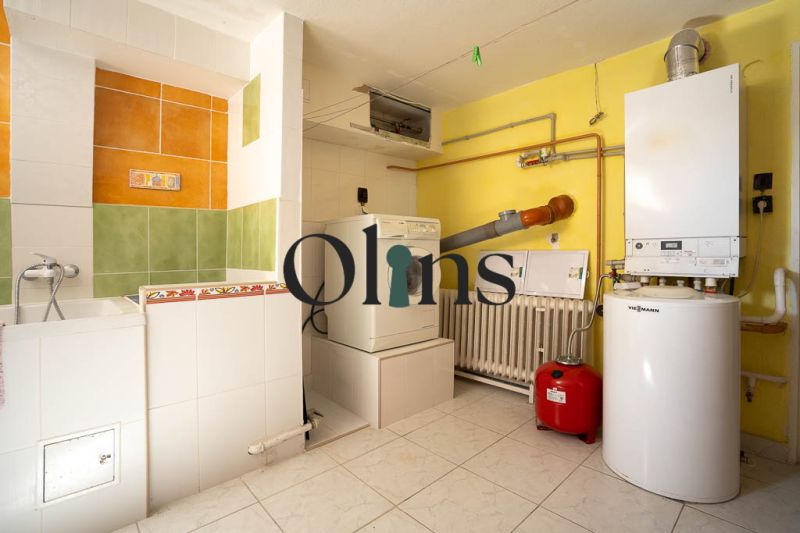 Boiler room in a family house with a washing machine, dryer, and boiler, light tiles.