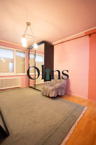 A room in a family house with a wooden decor floor, a mirrored wardrobe, and an armchair.