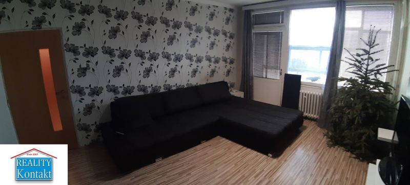 Living room in a 2-room apartment with floral wallpaper and a wooden decor floor.