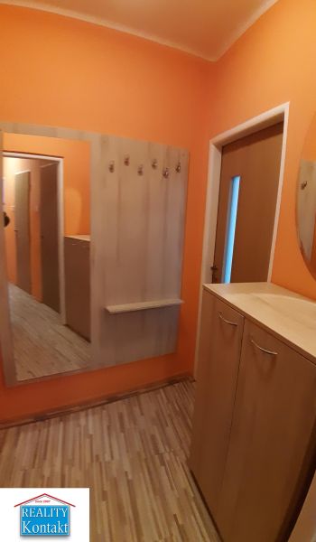 Orange hallway with a mirror, hooks, and a floor with a wooden decor in a 2-room apartment.