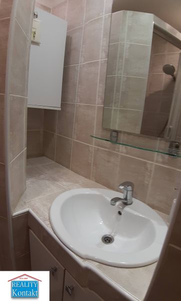 A small bathroom with a sink and a mirror in a 2-room apartment.