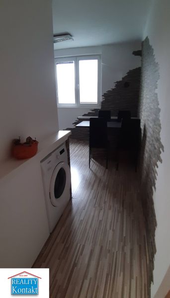 Dining area with wood-patterned flooring, a washing machine, and an interesting wall in a 2-room apartment.