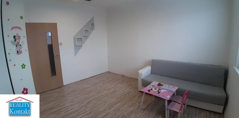 Living room in a two-room apartment with a wooden decor floor and children's furniture.