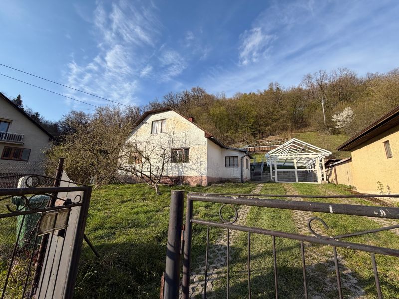 A family house in Štós with a shelter in the yard, green lawn, surrounded by nature.