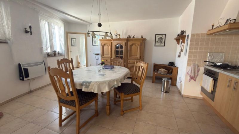 A kitchen in a family house with a round table, wooden chairs, and a sideboard.