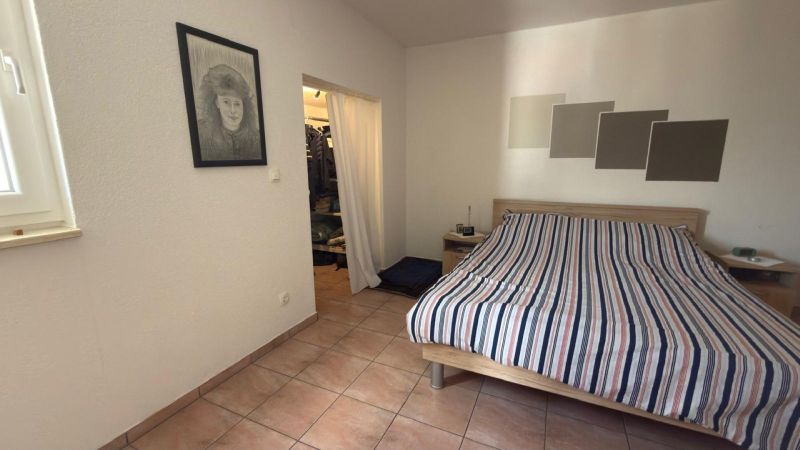 Bedroom with ceramic tiles, wall drawing, and bed in a family house.