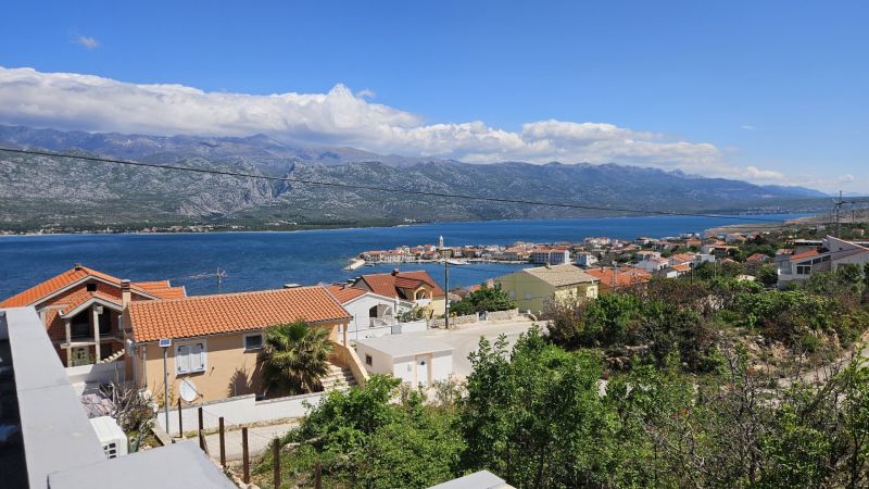 View of the coast and a family house in the town of Vinjerac with mountains in the background.