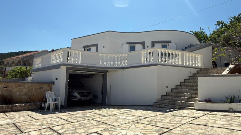A family house in Vinjerac with a white facade, stone paving, and railing.