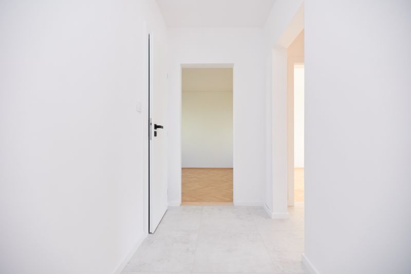 A hallway in a 3-room apartment with white walls and a floor with a wood decor.