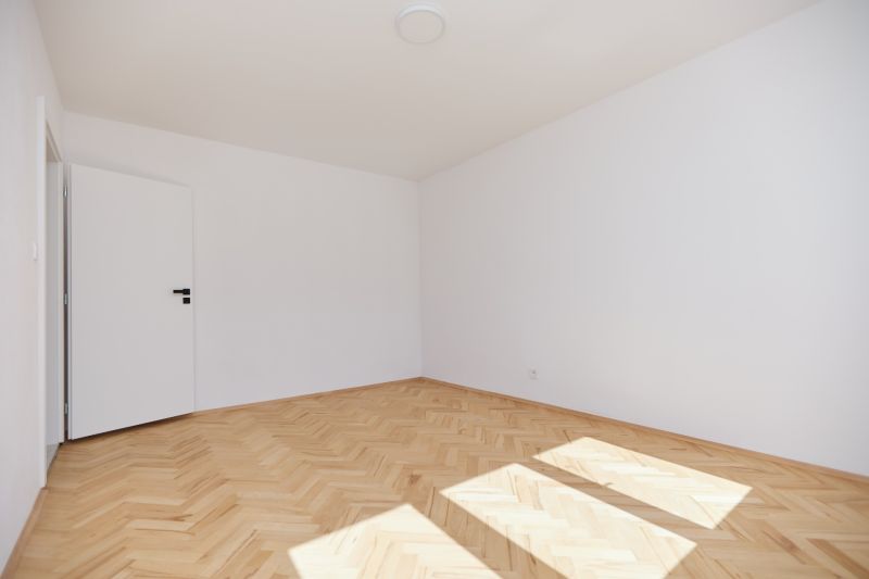 An empty room in a 3-room apartment with a wooden decor floor.