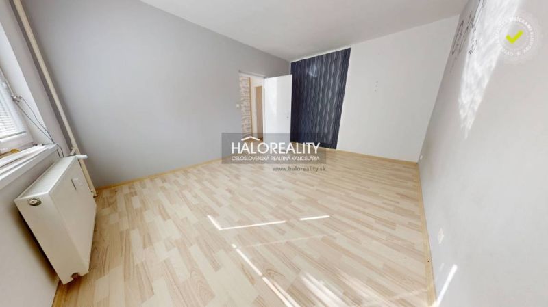A room in a one-room apartment with a wooden decor floor and gray walls.