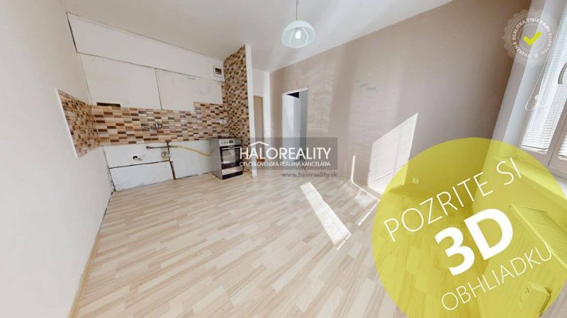 A room with a wooden decor floor and a kitchenette in a studio apartment.