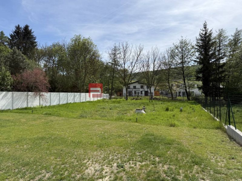 A garden with a lawn on a property in Borinka, surrounded by trees and a white fence. Plots - residential.