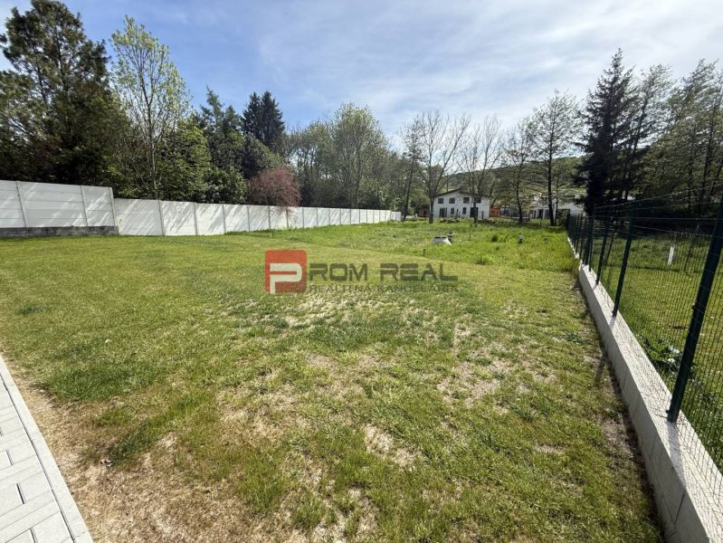 A green lawn on a residential plot in Borinka, Borinka Street, surrounded by a fence.
