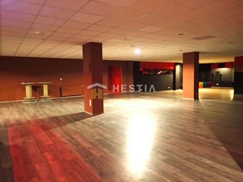 A large open space with wooden floors and columns suitable for commercial premises.