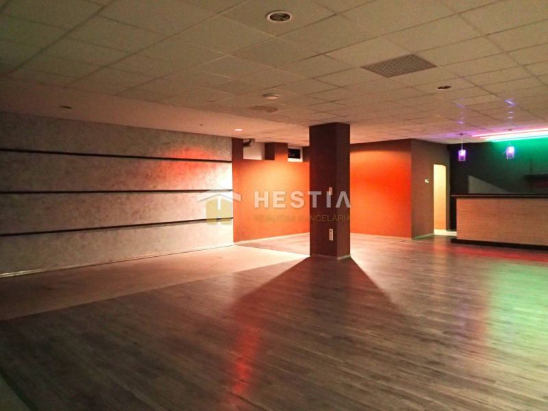 A large room with wooden flooring and colorful lighting, suitable for commercial spaces.