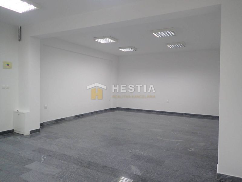 A spacious office with tiled flooring and lighting. Suitable for commercial land.