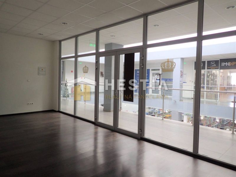 A vacant space in a 2-room apartment with large glass doors and a dark floor.